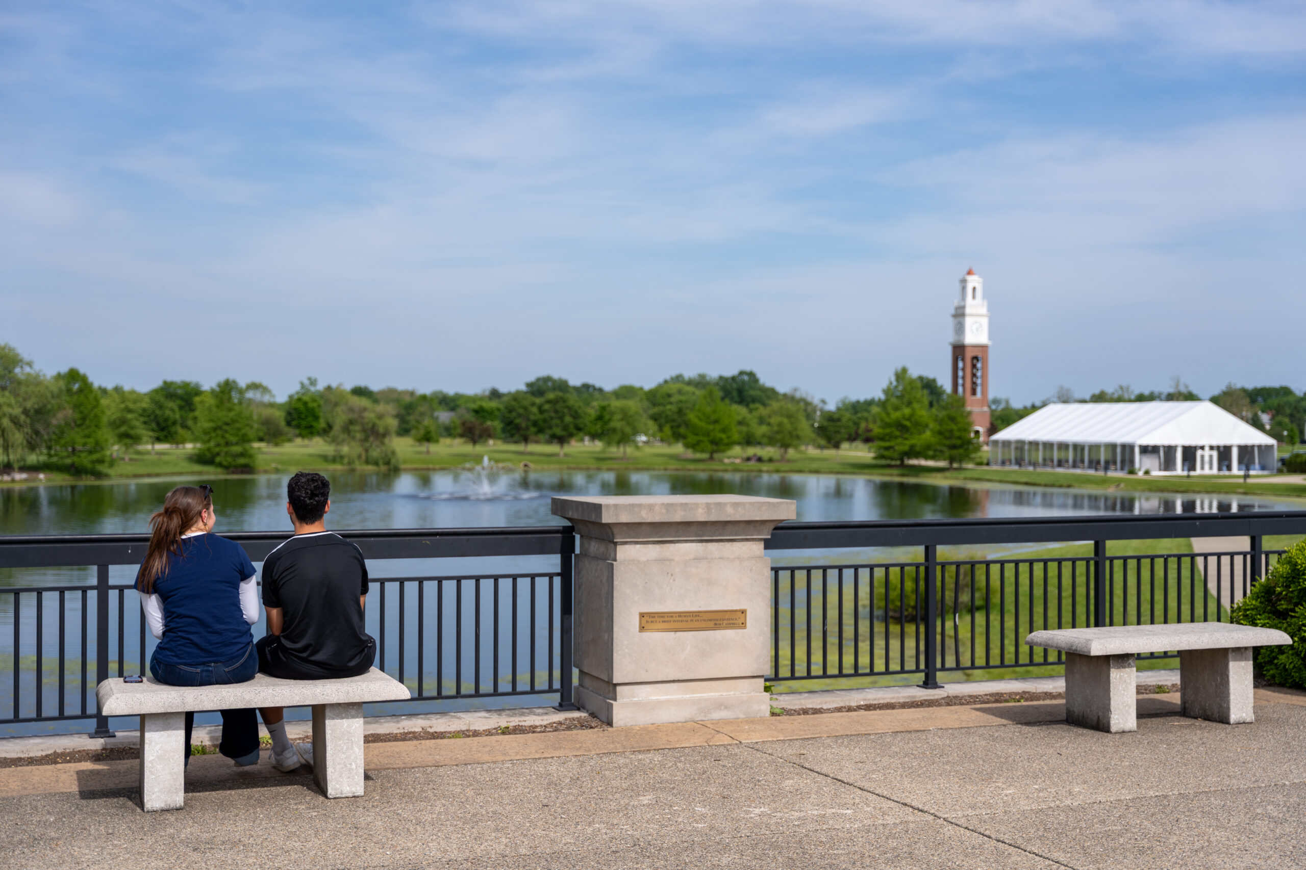 Two people sitting on a bench overlooking a water feature in Carmel, Indiana